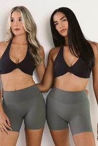 Two women modeling matching high-waisted stone athletic biker shorts and black crops against a plain light background.