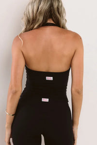 Rear view of a woman wearing a black halter-style singlet and shorts with ELE logos