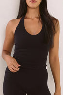 A woman wearing a black halter tank top, shown from a front profile against a plain light background.